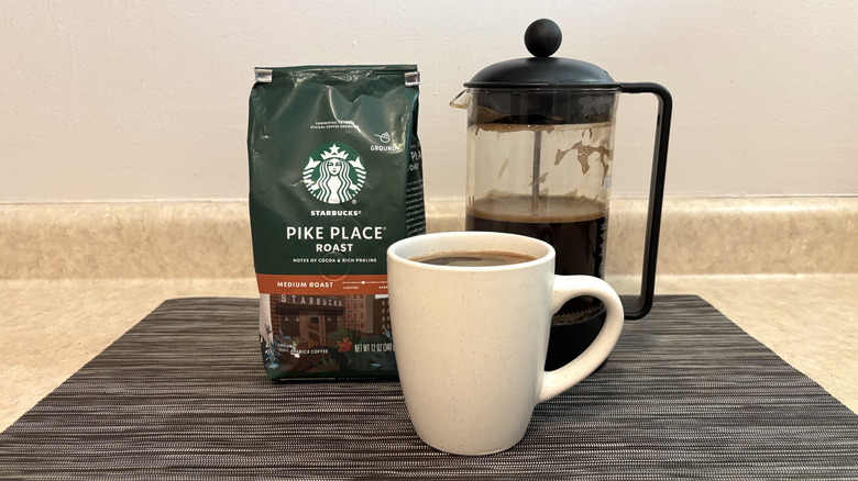 Starbucks Pike Place coffee in french press, cup, and bag on black placemat