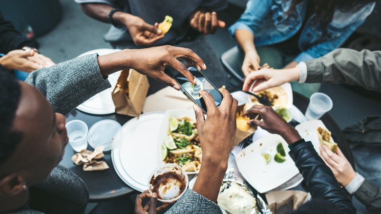 Person with friends photographing food