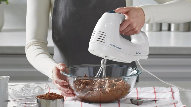 A person using a Hamilton Beach hand mixer