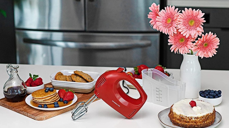 An OVENTE hand mixer on the counter with several food items