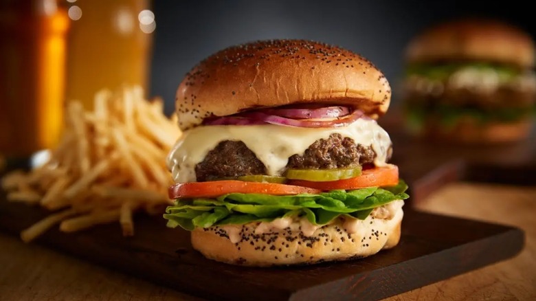 Burger with poppy seed bun, cheese, lettus, and tomato