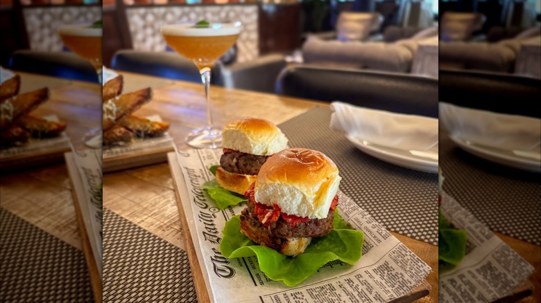 Two meatball sliders on a table with cocktail