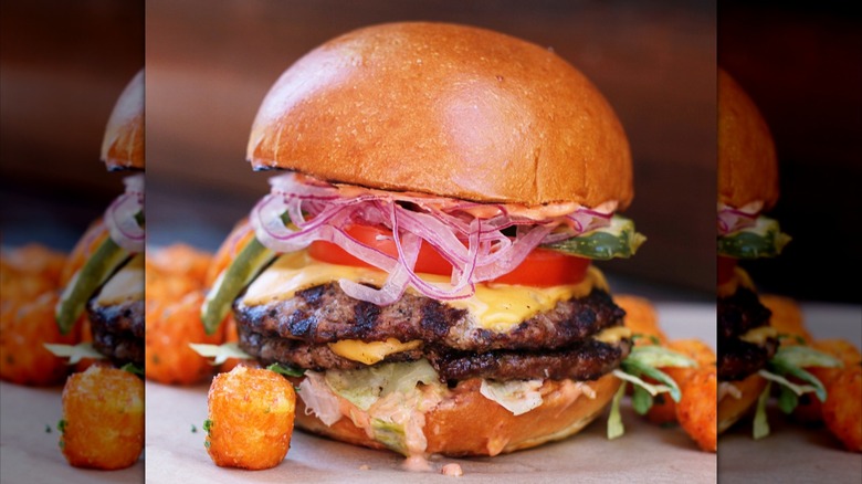 Burger with two patties, cheese, lettuce, onion, and tomato