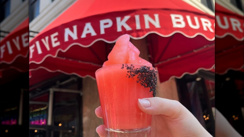 frozen margarita being held up in front of 5 Napkin Burger