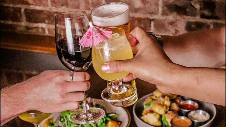 three people clinking their glasses together at a restaurant