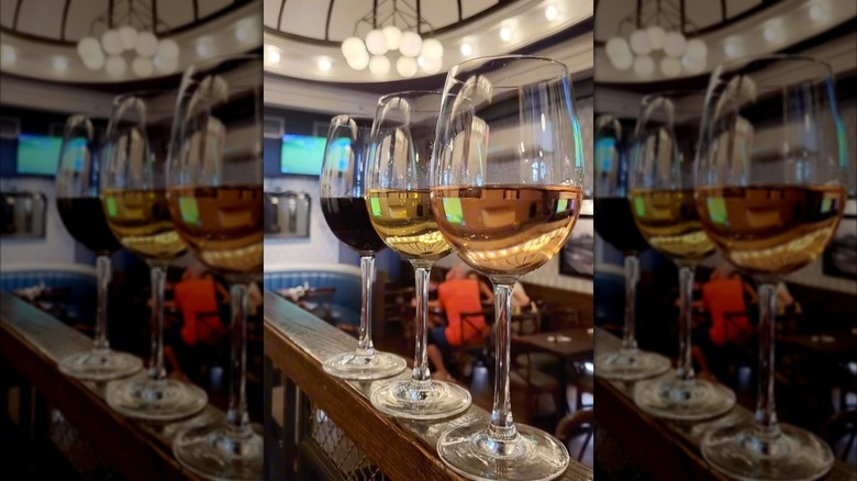 three glasses of wine lined up at the edge of a banister
