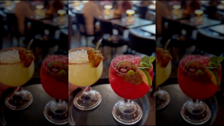 two brightly colored cocktails on a serving tray at a restaurant