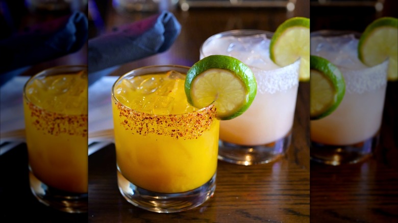 two flavored margaritas side by side with a lime wedge in each