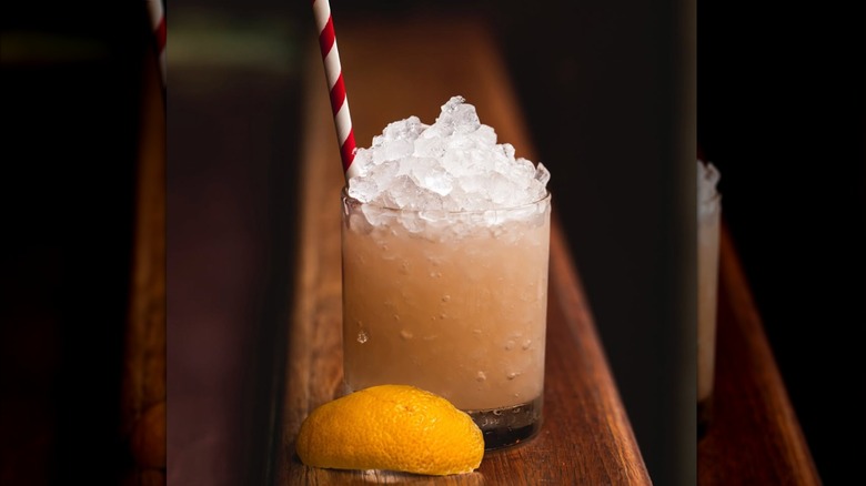 close up of a cocktail filled with ice and a lemon wedge to the side