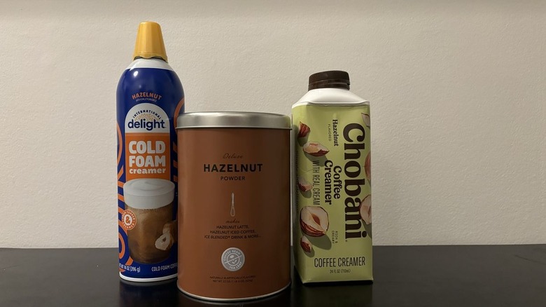 Three hazelnut coffee creamers on black table