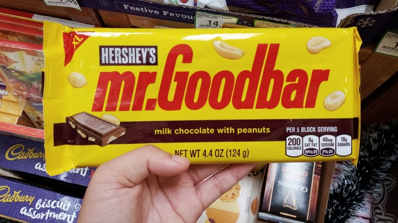 Hand holding a bar of Hershey's Mr. Goodbar in a candy aisle