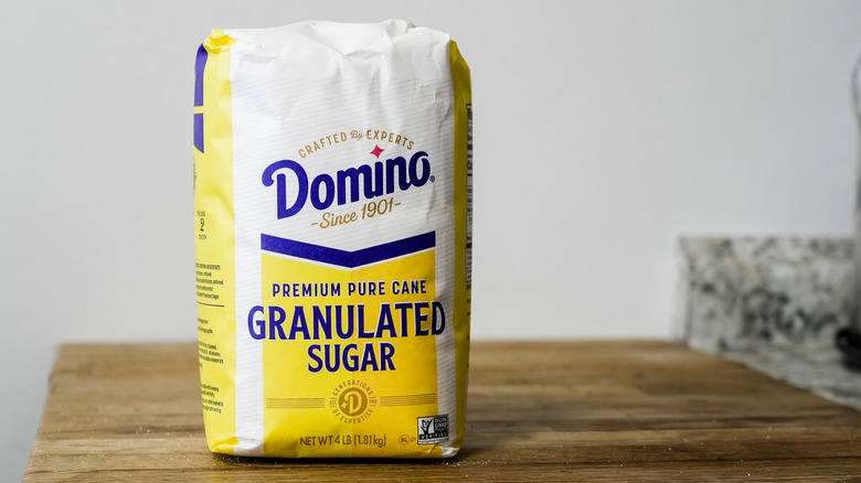 A yellow and white bag of Domino brand granulated sugar sitting on a kitchen counter