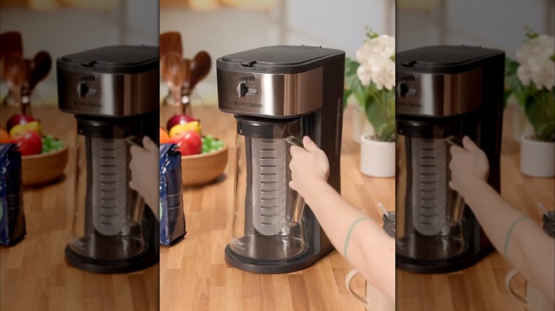 A person holding the pitcher from a West Bend iced tea maker