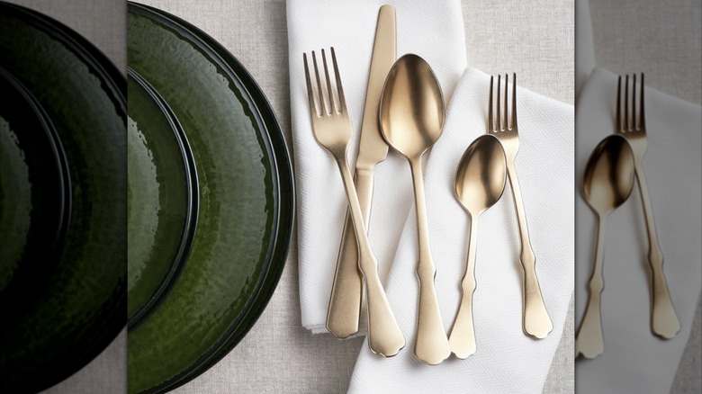 Five pieces of golden cutlery next to a green plate