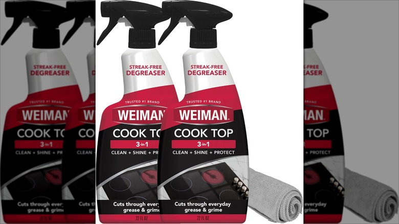 Two bottles of Weiman Cooktop Cleaner Spray with towel on white background
