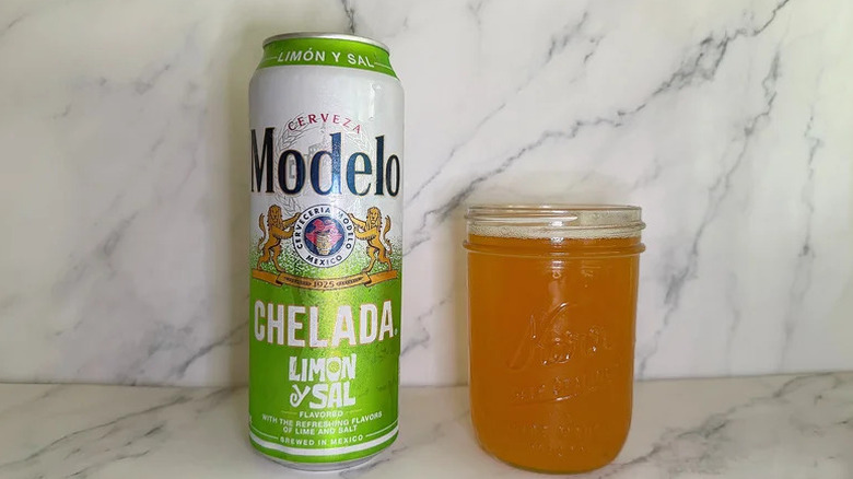 A can of Modelo Chelada Limon y Sal next to a glass jar filled with the beer