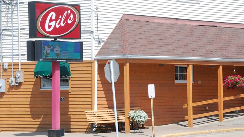 A restaurant with a 'Gil's sign out front and a wooden bench