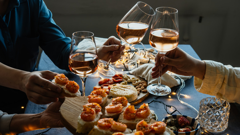 People toasting and passing snacks on wooden boards