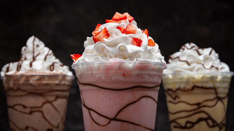 three milkshakes topped with whipped cream