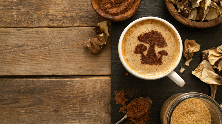 Cup of coffee with mushroom art, on a wooden table with dried mushrooms