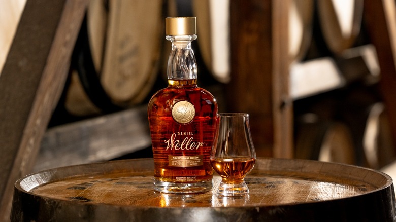 Bottle of Daniel Weller Spelt Wheat bourbon with a glass on barrel