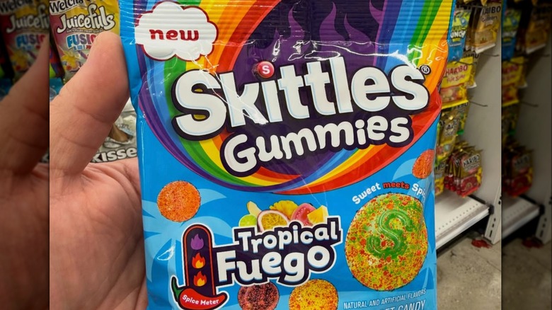 customer holding SKITTLES Gummies Fuego