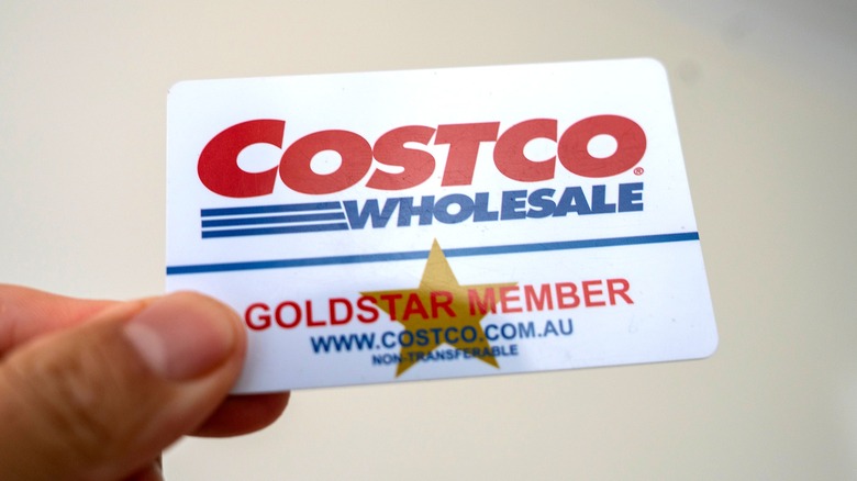 Hand holding blue, red, and white Costco Wholesale gold star membership card