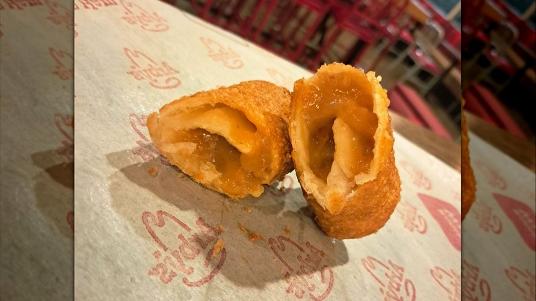 Arby's Peach Cobbler Roll dessert cut in half sitting on paper placemat with Arby's logo