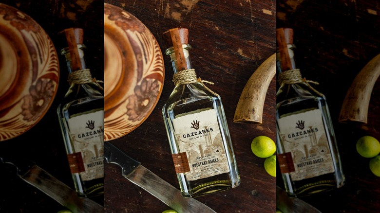 Bottle of Cazcanes Nuestras Raices on table beside knife, bowl, and limes