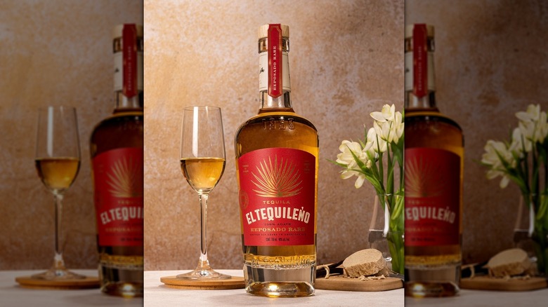 Bottle of El Tequileño Reposado Rare tequila next to flute of tequila on table