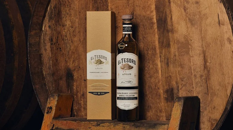 Bottle of El Tesoro Mundial: Yamazaki Edition tequila with barrel behind