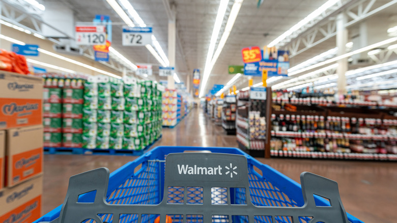 A Walmart shopping cart at the beginning of a long grocery aisle