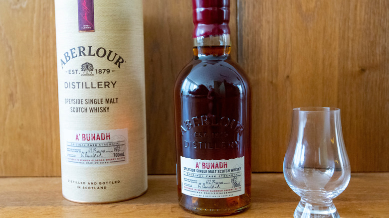 Bottle of Aberlour A'bunadh on a wooden surface with its packaging and an empty glass on either side
