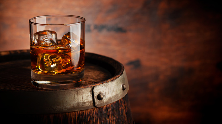 Glass of whisky perched on top of a barrel