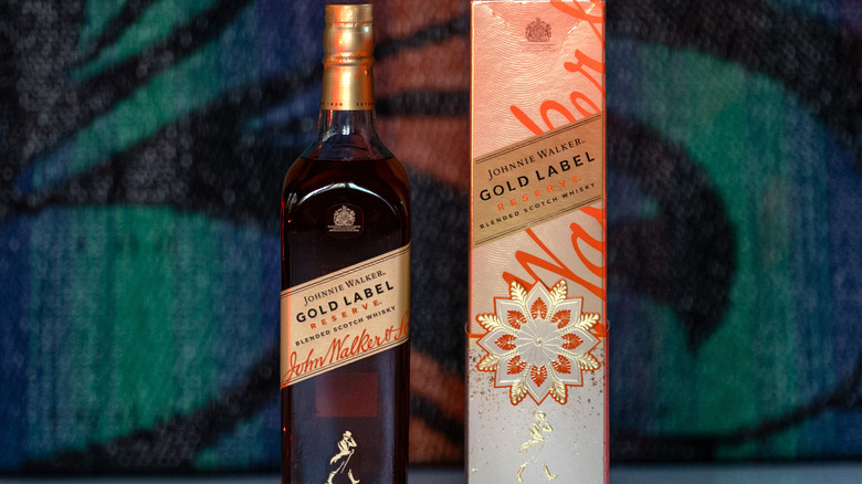 Bottle of Johnnie Walker Gold Label Reserve next to its packaging against a colorful background