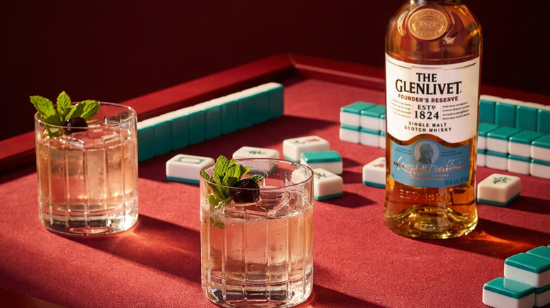 Bottle of The Glenlivet Founder's Reserve on a table with two filled drinks and mahjong puzzle pieces