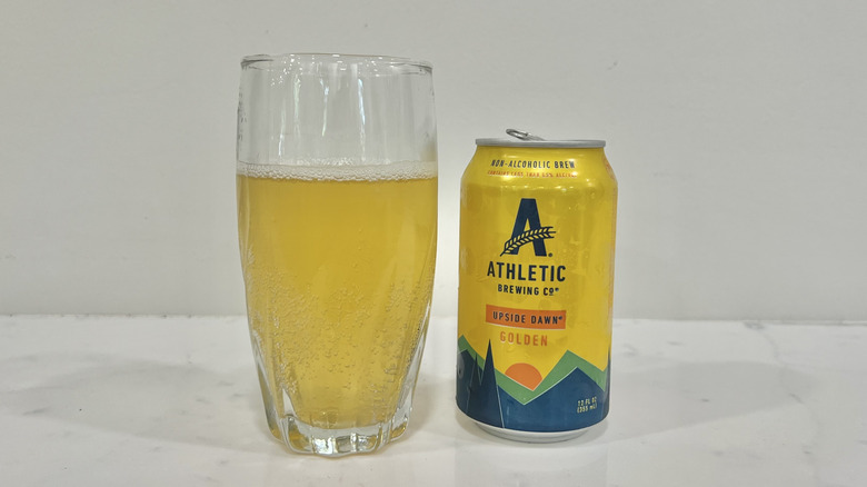 A glass of Upside Dawn Golden by Athletic Brewing Co. next to a can