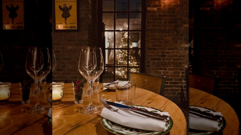 Table set for dinner with plate and wine glass with brick wall in background