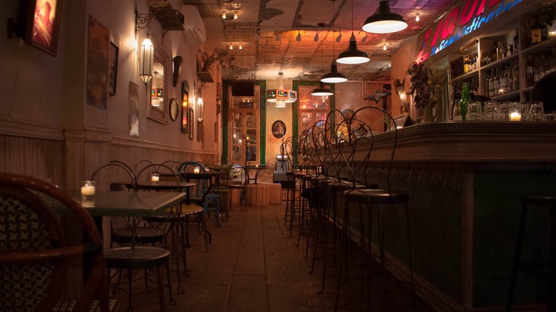 Looking down the aisle between tables against a wall and bar