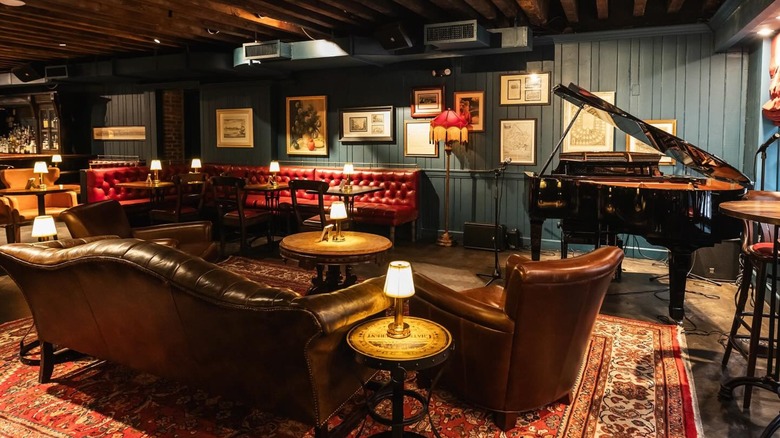 Leather sofas, chairs, and tables in room with piano