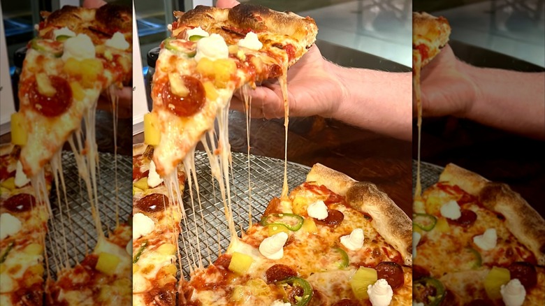 Hand picking up a piece of pizza from the tray