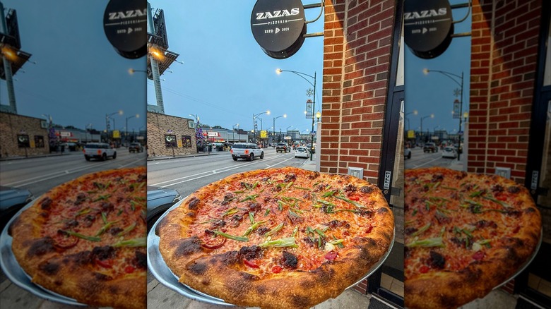 Pizza on a tray outside Zazas with restaurant sign