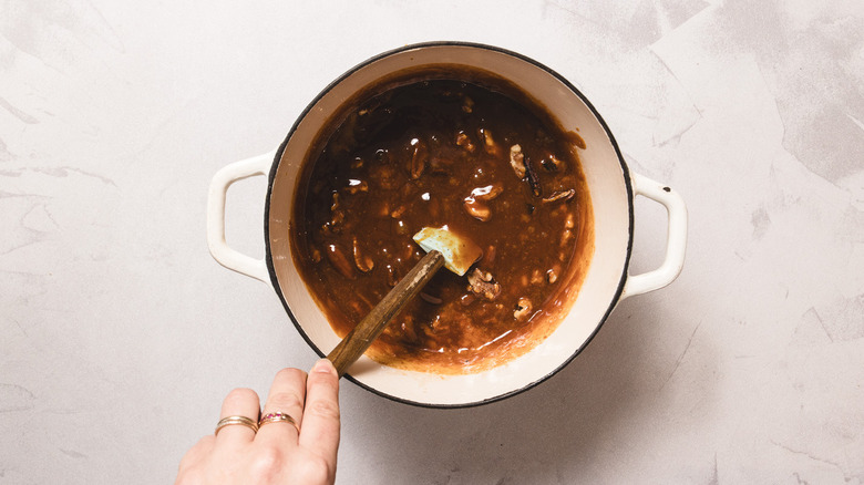 Stirring candy mixture with nuts in white pot