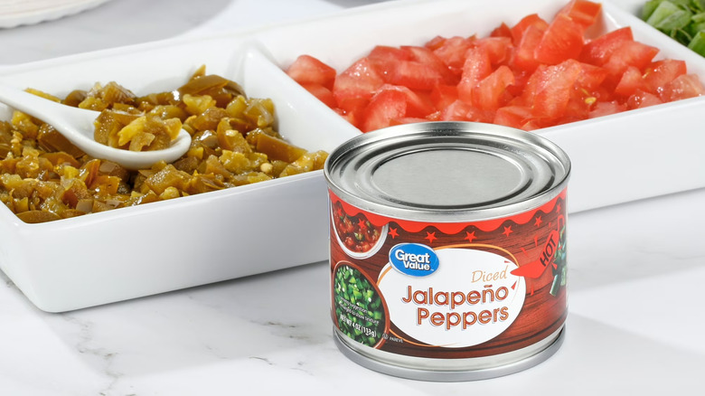 A small can of Jalapeño Peppers in front of a serving tray with peppers and tomatoes