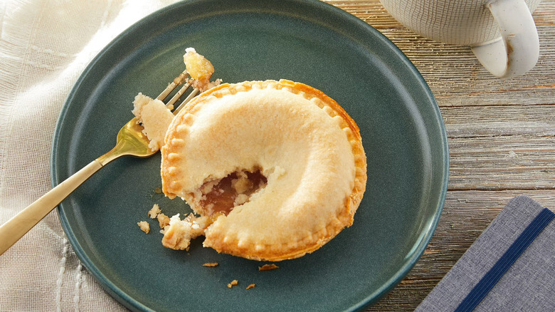 Tiny pie with a chunk of it missing, taken out by a golden fork
