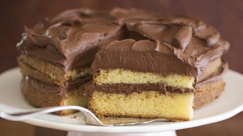 yellow cake with chocolate frosting with slice cut out
