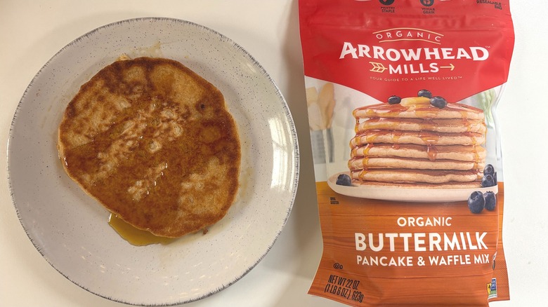 Arrowhead Mills Organic Buttermilk pancake mix next to plate with cooked pancake on white table