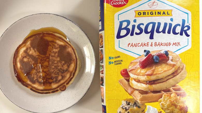 Bisquick Original pancake mix next to plate with cooked pancake on white table