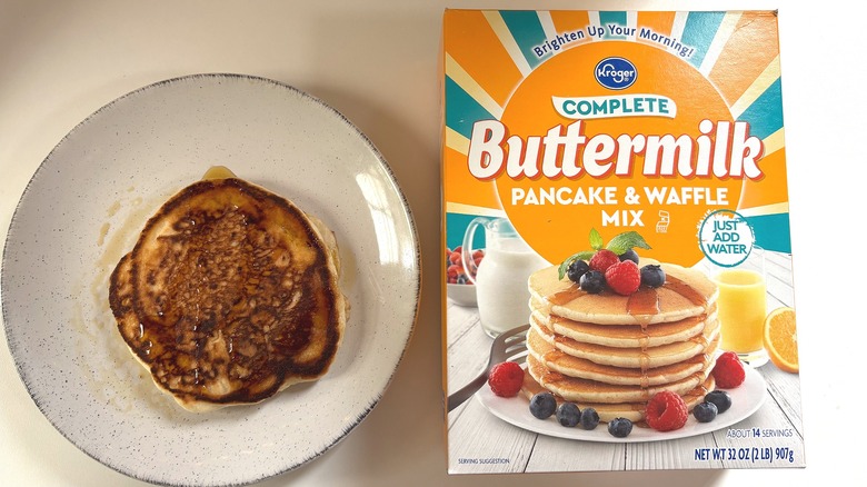 Kroger Buttermilk pancake mix next to plate with cooked pancake on white table