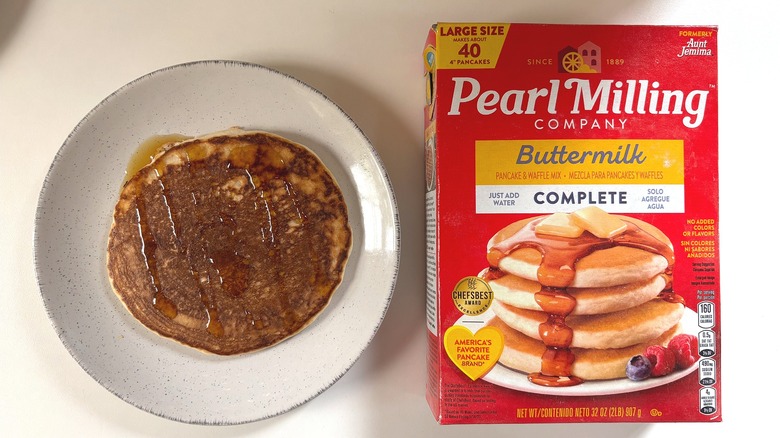 Pearl Milling Company Buttermilk pancake mix next to plate with cooked pancake on white table